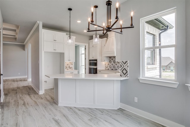 kitchen featuring hanging light fixtures, white cabinetry, backsplash, and a wealth of natural light