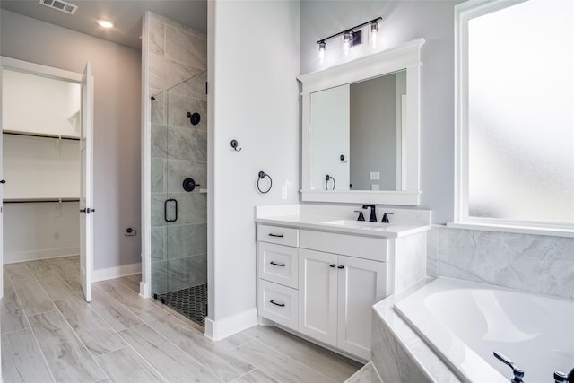 bathroom featuring vanity, separate shower and tub, and hardwood / wood-style flooring