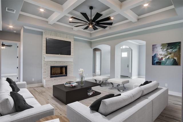 living room featuring a fireplace, beam ceiling, ceiling fan, and light hardwood / wood-style flooring