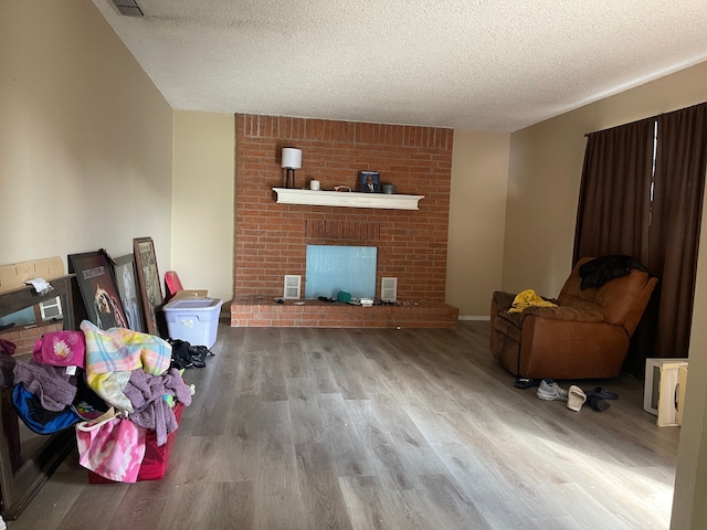 living room featuring light hardwood / wood-style floors, a fireplace, and a textured ceiling