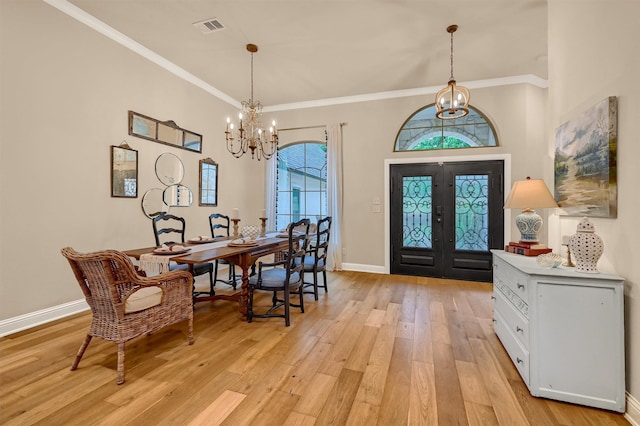 dining room featuring french doors, light hardwood / wood-style flooring, crown molding, and a notable chandelier