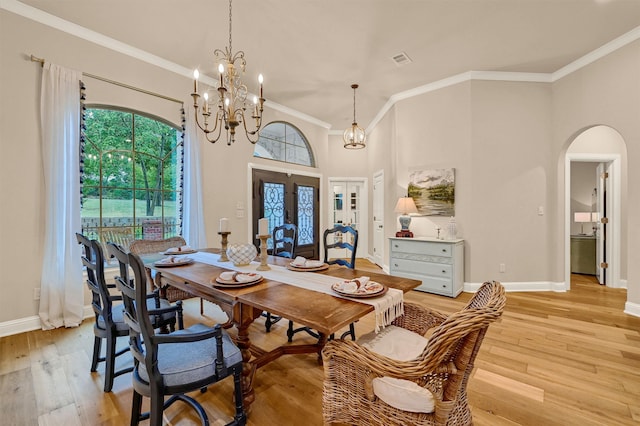 dining area with crown molding, french doors, an inviting chandelier, and light wood-type flooring