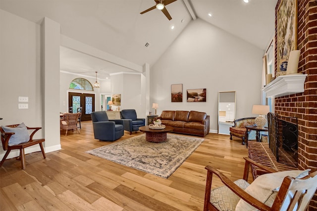 living room featuring ceiling fan, beam ceiling, a fireplace, and light hardwood / wood-style flooring