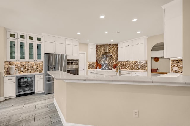 kitchen featuring white cabinets, kitchen peninsula, stainless steel appliances, and wine cooler