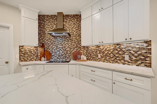 kitchen with white cabinetry, decorative backsplash, wall chimney exhaust hood, and light stone countertops