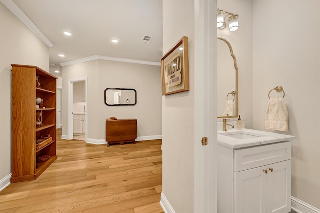 corridor featuring light hardwood / wood-style floors, crown molding, and sink