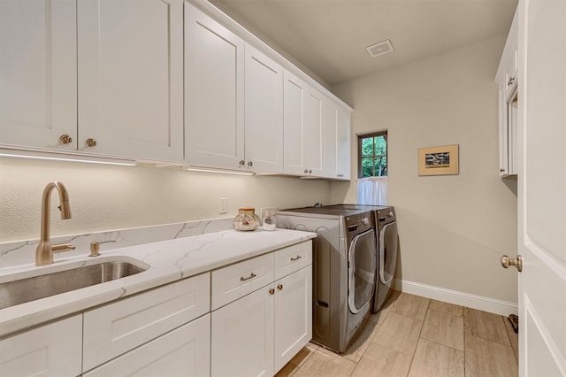 laundry room with cabinets, separate washer and dryer, and sink