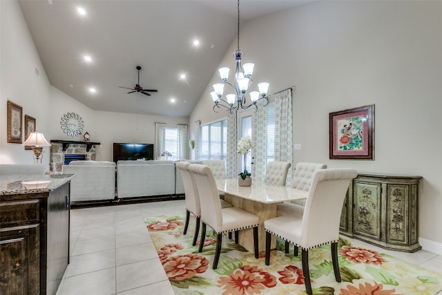 dining room with a fireplace, ceiling fan with notable chandelier, light tile patterned floors, and high vaulted ceiling