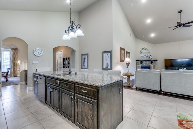 kitchen with high vaulted ceiling, pendant lighting, sink, and a center island with sink