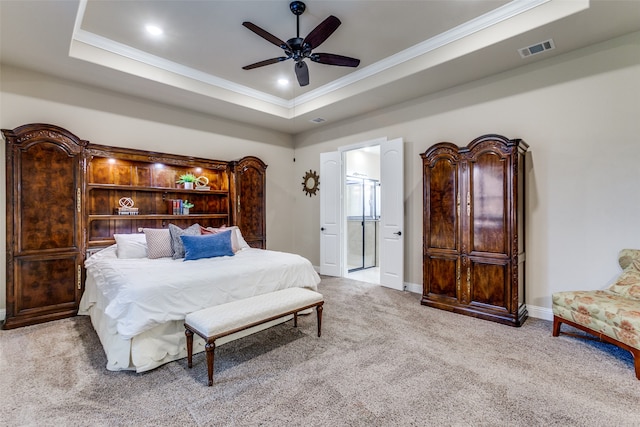 bedroom featuring ornamental molding, connected bathroom, a tray ceiling, light colored carpet, and ceiling fan