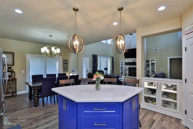 kitchen with dark hardwood / wood-style floors, pendant lighting, a center island, and blue cabinetry