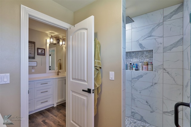 bathroom with wood-type flooring, vanity, and tiled shower