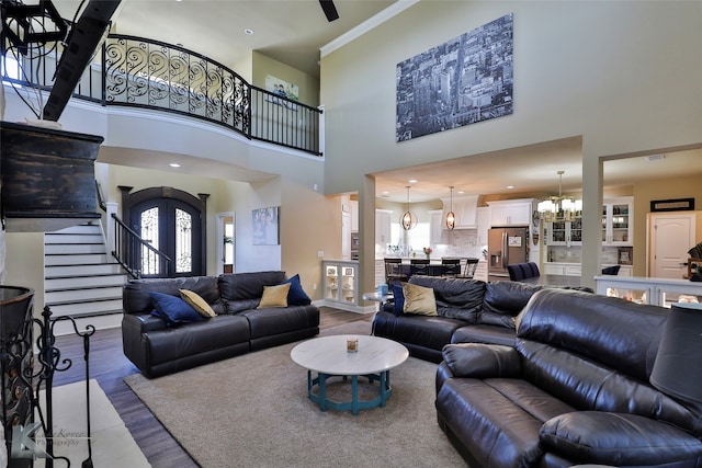 living room with hardwood / wood-style flooring, crown molding, a towering ceiling, and a notable chandelier