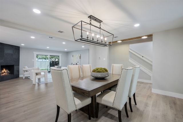 dining space featuring a tile fireplace and light wood-type flooring