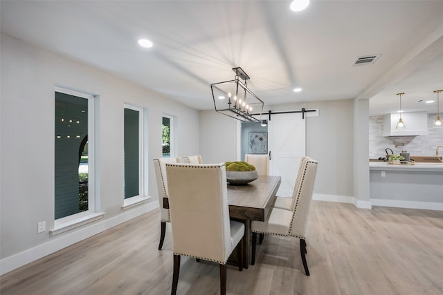 dining area with a barn door and light hardwood / wood-style floors