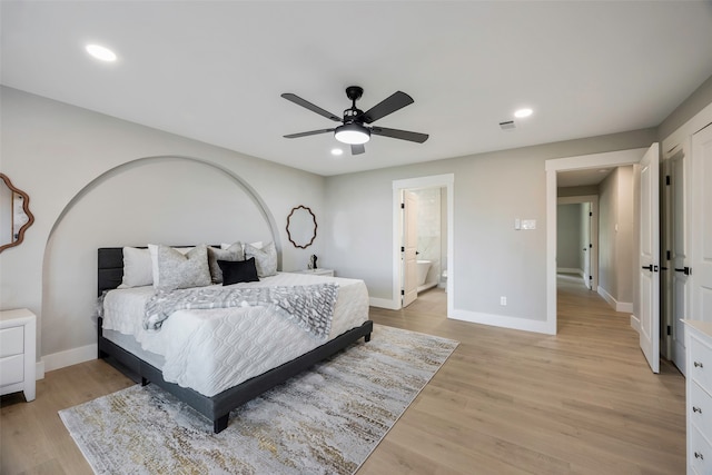 bedroom with light hardwood / wood-style floors, ceiling fan, and connected bathroom