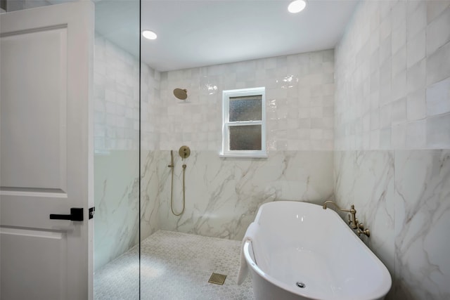 bathroom with tile walls and shower with separate bathtub