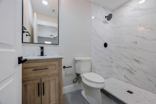 bathroom with tile patterned flooring, tiled shower, toilet, and vanity