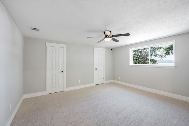 carpeted empty room featuring a textured ceiling and ceiling fan