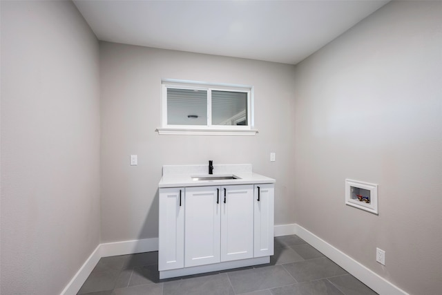 laundry room featuring cabinets, washer hookup, sink, and dark tile patterned floors