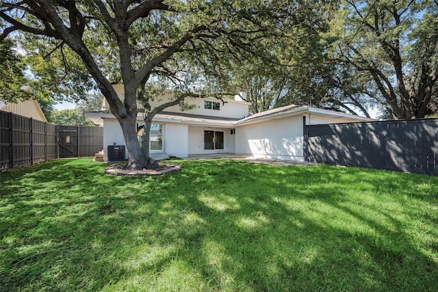 rear view of house with central AC and a yard