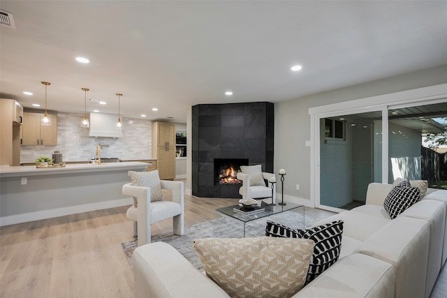 living room with a tiled fireplace and light hardwood / wood-style floors