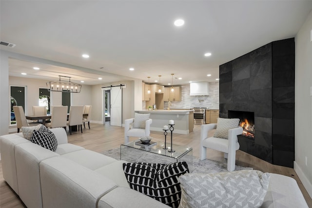 living room with light wood-type flooring, a fireplace, a barn door, and sink