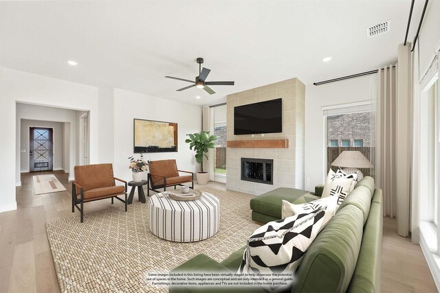 living room featuring a tile fireplace, ceiling fan, and light wood-type flooring