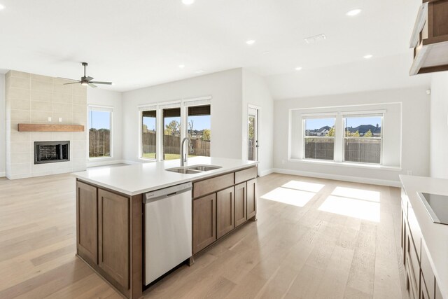 kitchen with ceiling fan, dishwasher, sink, an island with sink, and light hardwood / wood-style floors