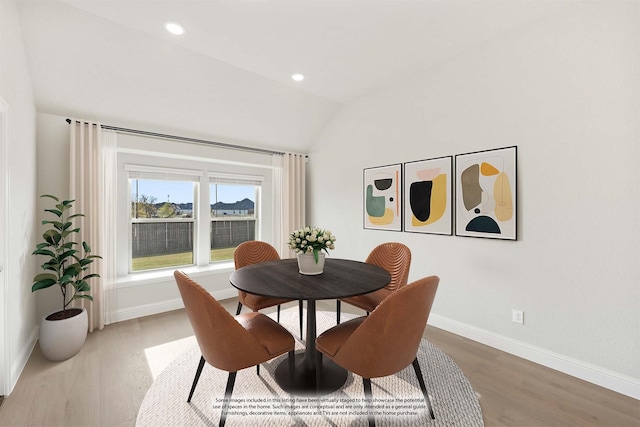 dining room with hardwood / wood-style flooring and vaulted ceiling