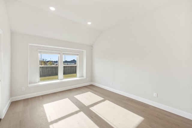 spare room featuring light hardwood / wood-style flooring and vaulted ceiling