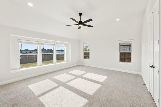 carpeted empty room with a wealth of natural light, lofted ceiling, and ceiling fan