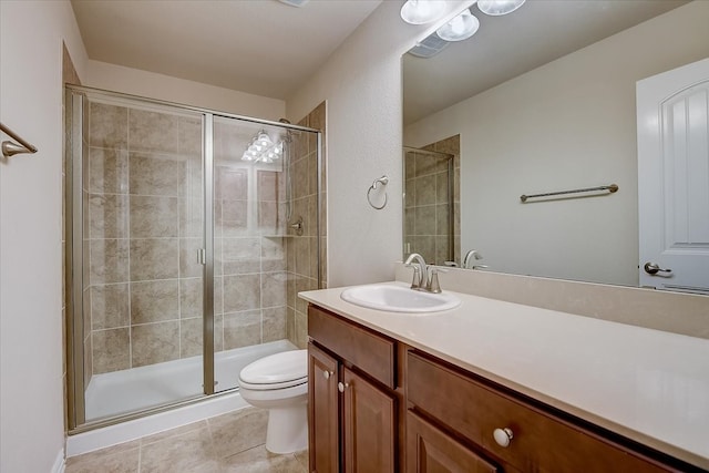 bathroom featuring tile patterned floors, a shower with door, vanity, and toilet