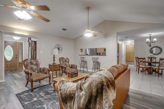 living room featuring hardwood / wood-style flooring, ceiling fan with notable chandelier, and vaulted ceiling