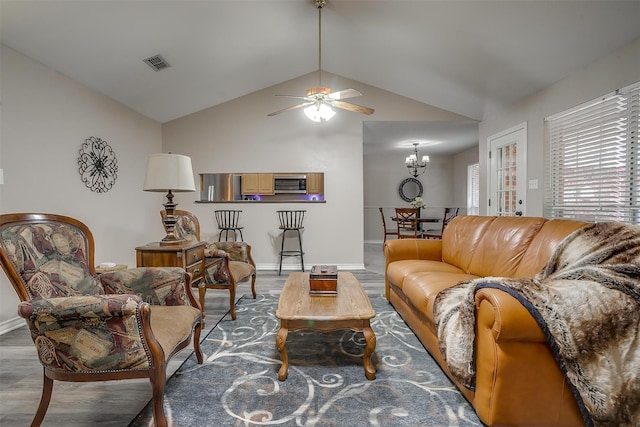 living room with ceiling fan with notable chandelier, lofted ceiling, and hardwood / wood-style flooring