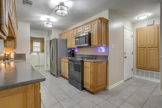 kitchen with washer and clothes dryer, light tile patterned floors, appliances with stainless steel finishes, and sink