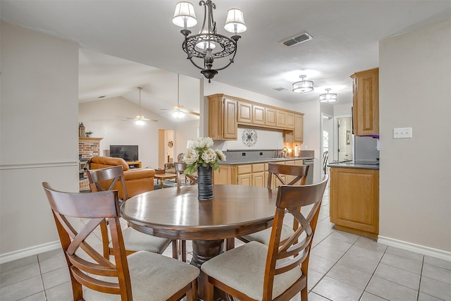 tiled dining room with ceiling fan, sink, a fireplace, and vaulted ceiling