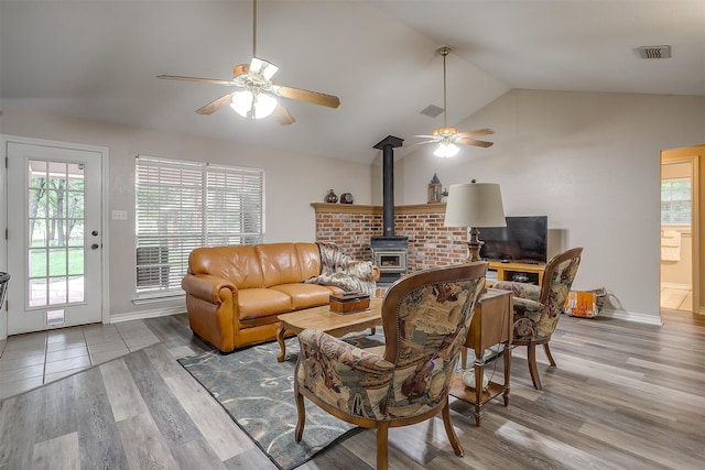 living room with vaulted ceiling, hardwood / wood-style floors, ceiling fan, and a wood stove