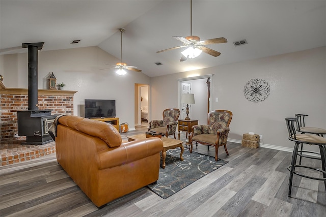 living room with a wood stove, vaulted ceiling, ceiling fan, and hardwood / wood-style flooring