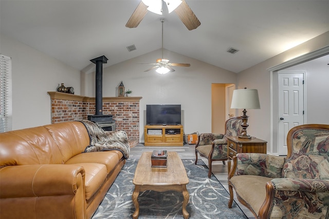 living room featuring vaulted ceiling, hardwood / wood-style floors, ceiling fan, and a wood stove