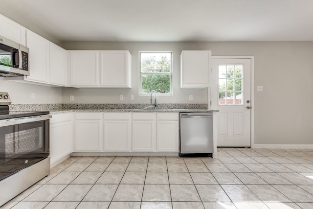 kitchen with white cabinetry, light stone counters, light tile patterned floors, stainless steel appliances, and sink