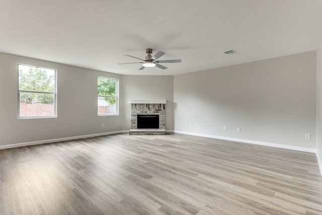 unfurnished living room with light hardwood / wood-style flooring, ceiling fan, and a brick fireplace