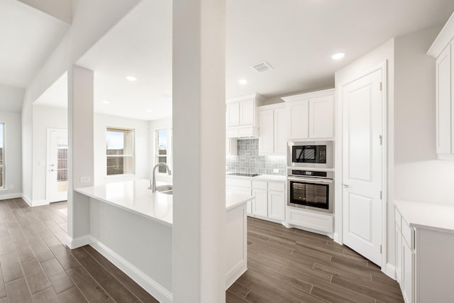 kitchen featuring white cabinetry, built in microwave, tasteful backsplash, and oven