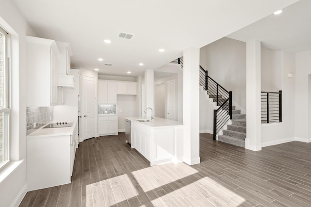 kitchen featuring sink, a kitchen island with sink, white cabinets, decorative backsplash, and stainless steel dishwasher