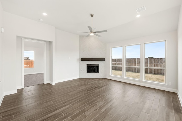 unfurnished living room featuring a large fireplace, dark hardwood / wood-style floors, and a wealth of natural light