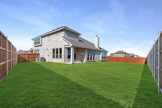 rear view of property with cooling unit and a yard