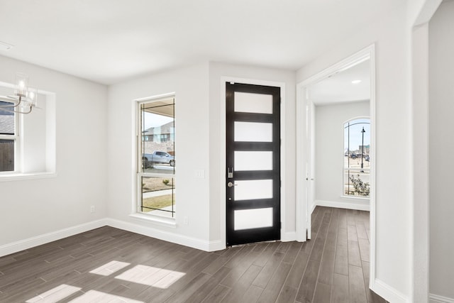 foyer featuring a healthy amount of sunlight, a notable chandelier, and dark hardwood / wood-style floors