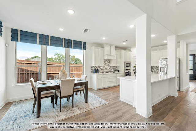 interior space featuring light wood-type flooring, decorative backsplash, and white cabinetry