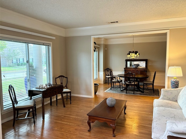 living room featuring a notable chandelier, a healthy amount of sunlight, a textured ceiling, and hardwood / wood-style floors