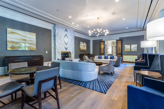 living room featuring wood-type flooring, a fireplace, ornamental molding, and an inviting chandelier